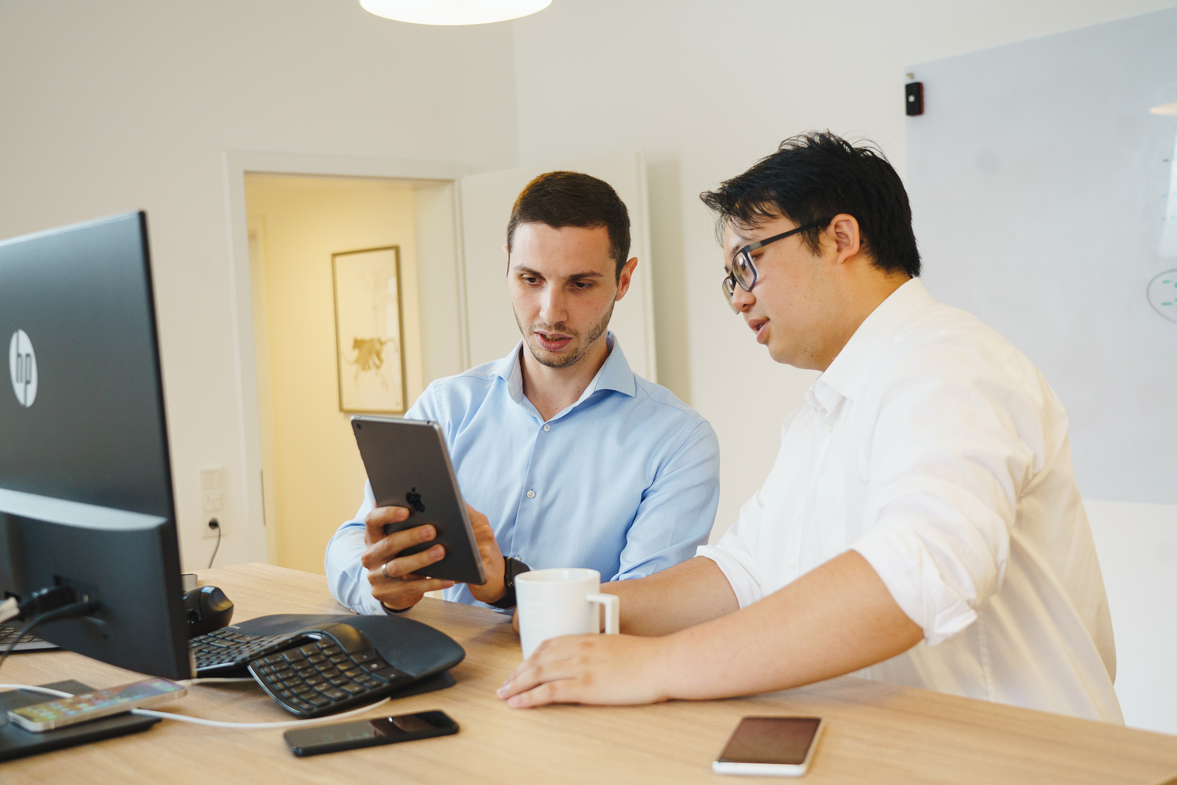 Zwei Entwickler der Cayas App-Agentur besprechen ein App-Projekt am Tablet im modernen Büro.