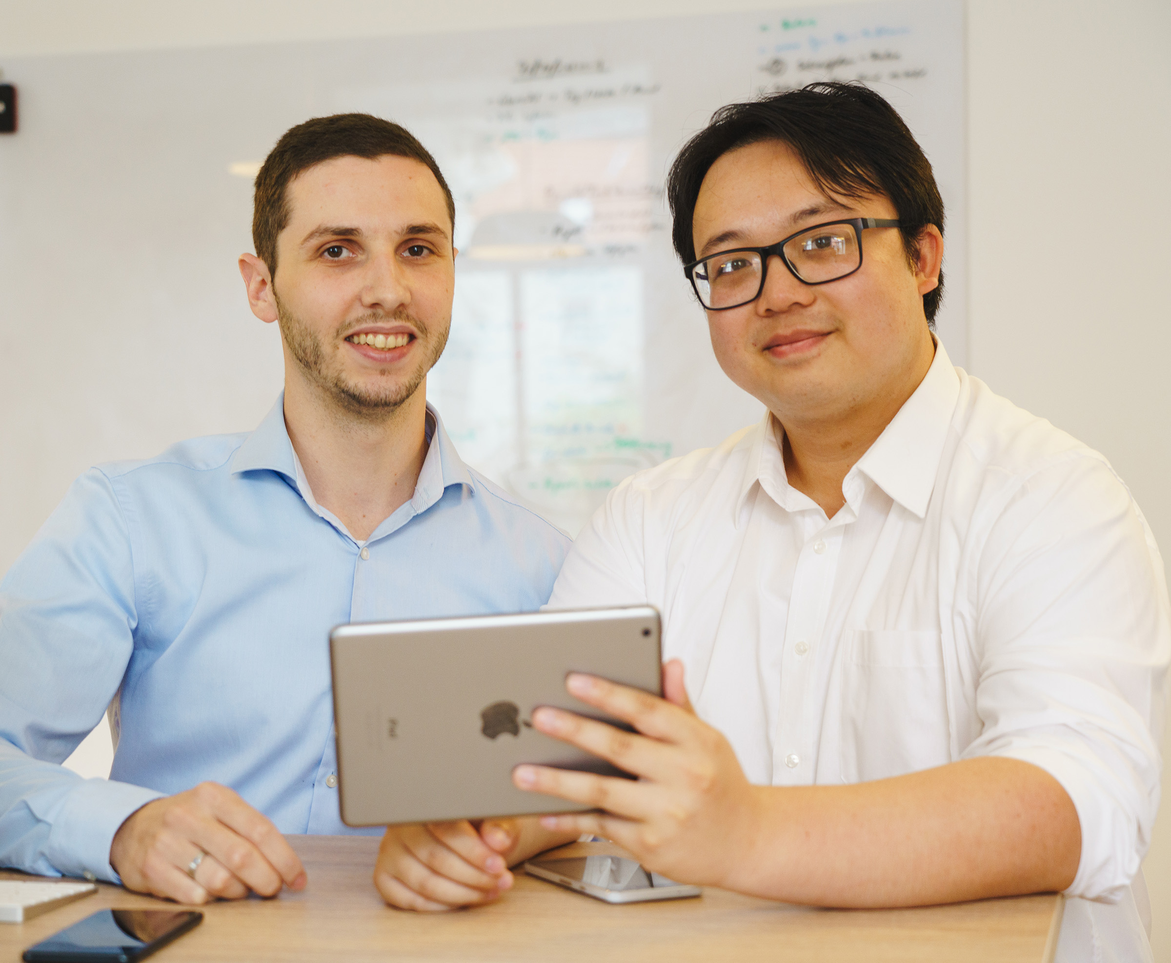 Zwei Softwareexperten der Cayas App-Agentur arbeiten gemeinsam an einem Tablet – Beispiel für Expert-as-a-Service-Unterstützung im B2B-Bereich.